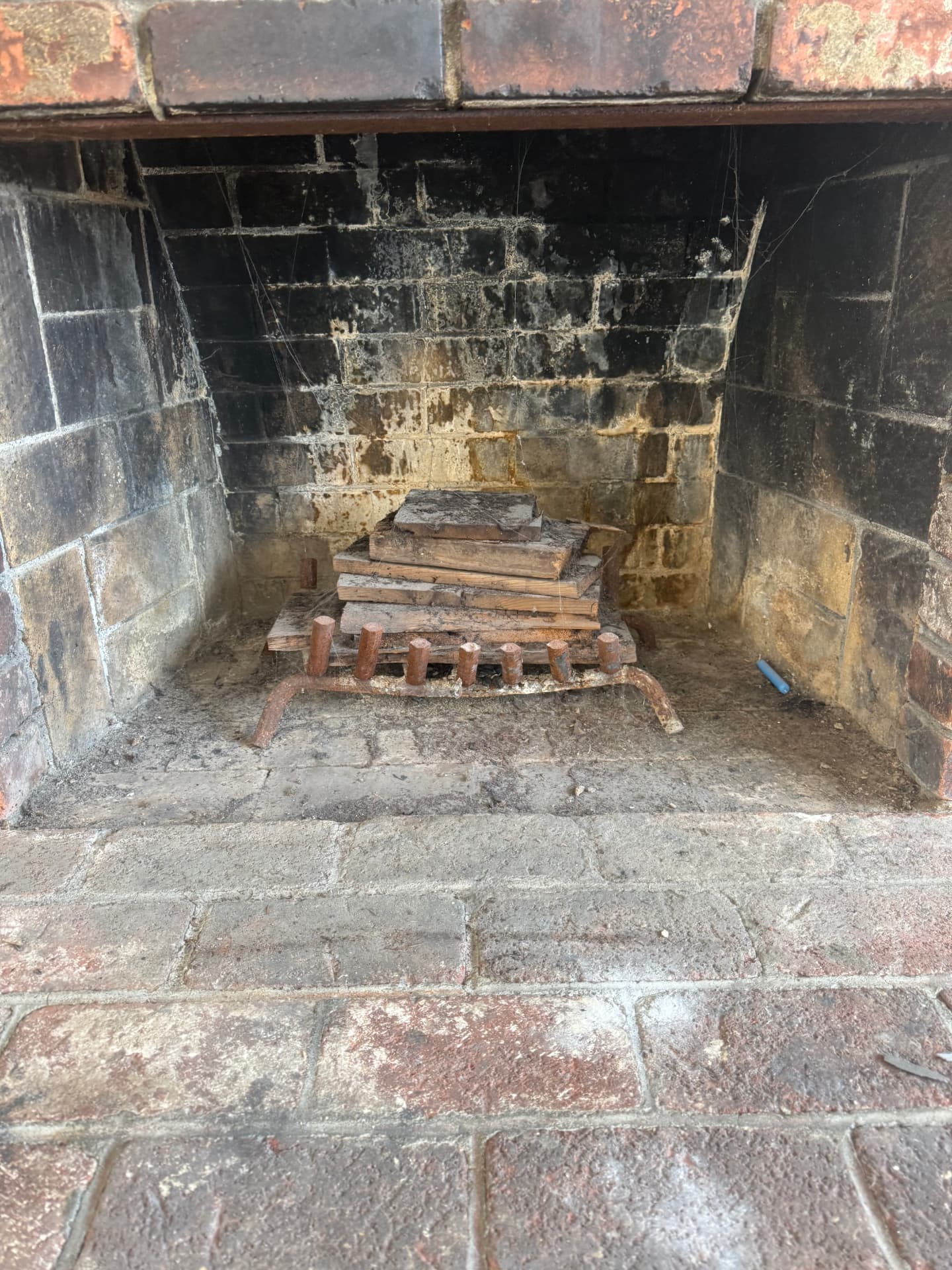 Soot-covered brick fireplace interior before professional cleaning — photo 1
