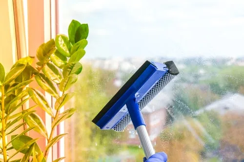 Professional window cleaner working across a large pane of residential glass