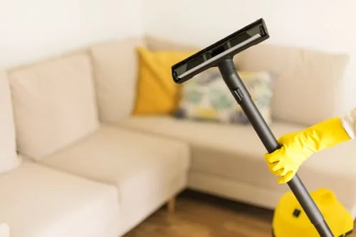 Cleaner in yellow gloves detailing an interior living room surface
