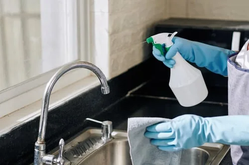 CH Cleaning technician cleaning a kitchen sink area during a residential service visit